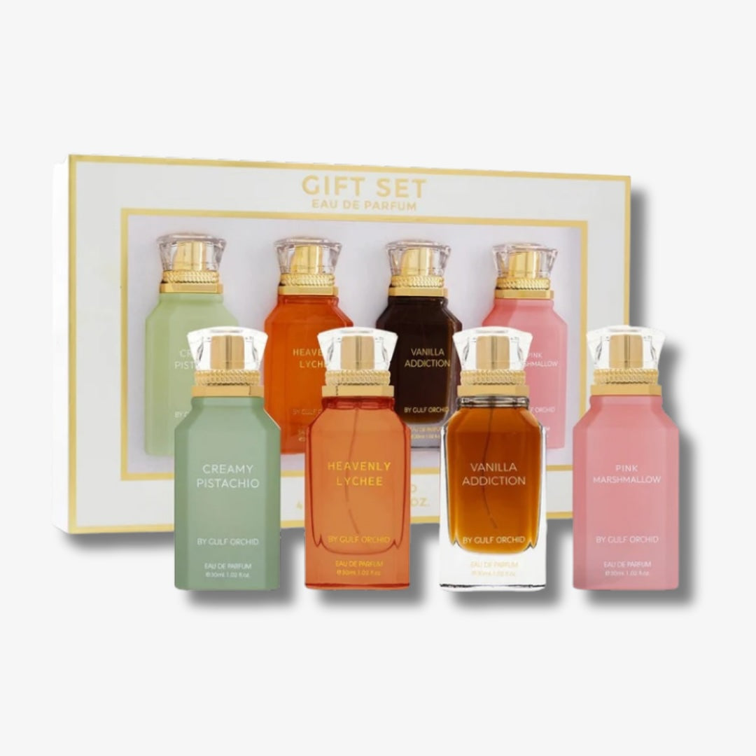 Set of five perfume bottles in various colors with a gift box in the background.